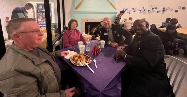 Neighbors around a purple-clothed table at the Prospect Lake beach house