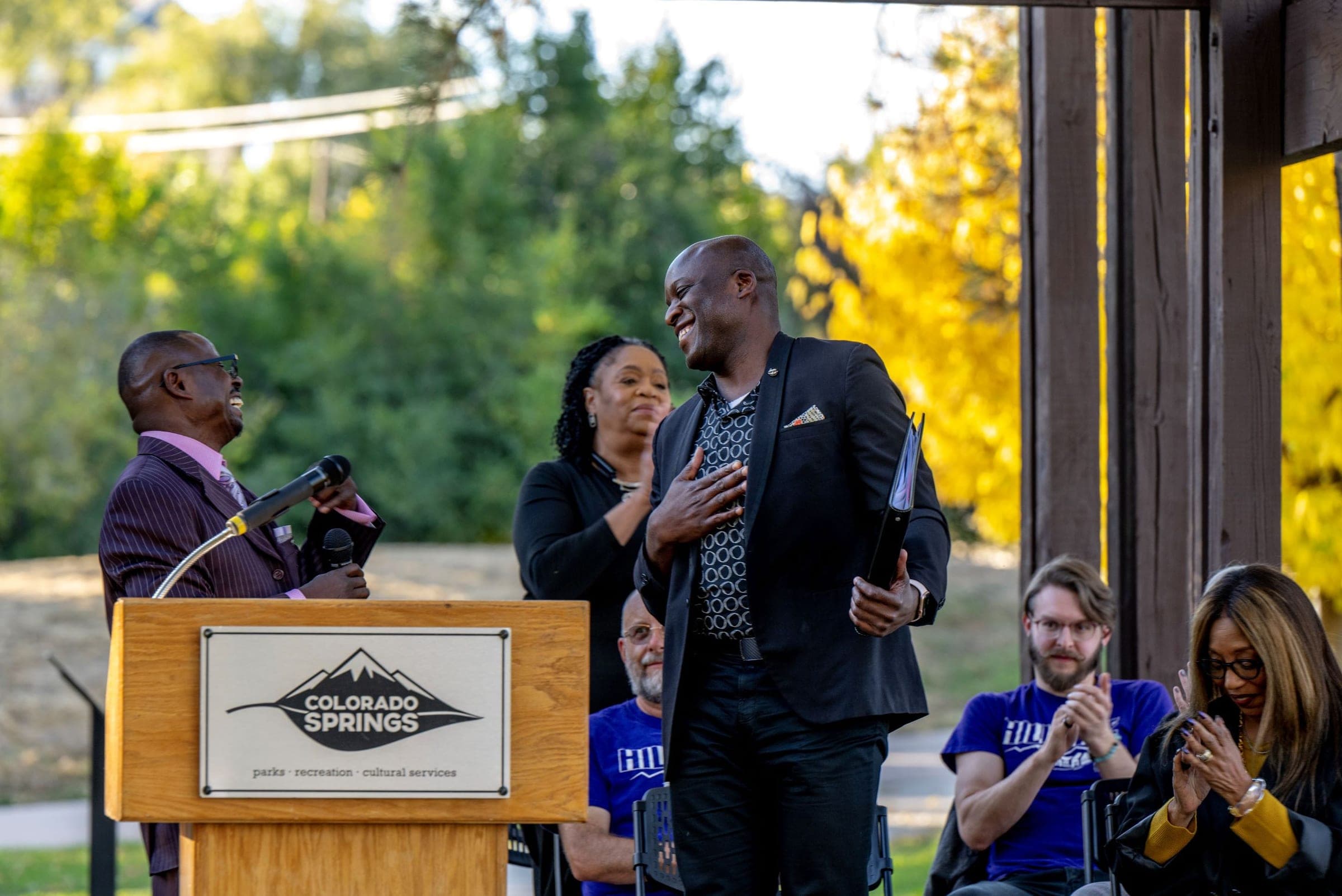 Neighbors applaud an honoree at the Leon Young Pavilion re-grand opening, with purple HILLSIDE shirts in the crowd